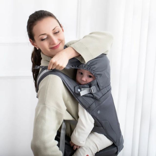 person carrying a baby in a hooded baby carrier