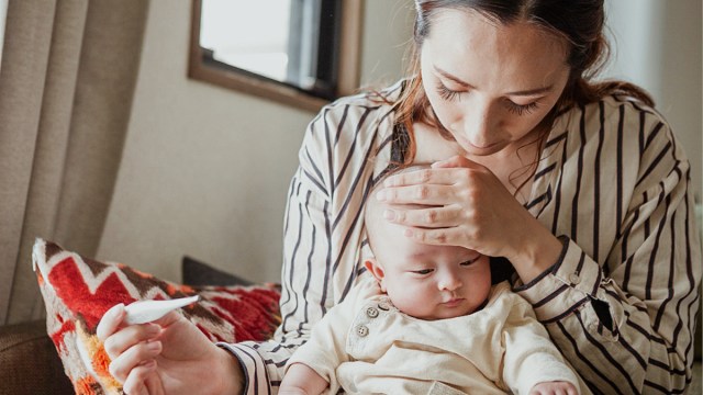 a mother taking her baby's temperature for a story on childrens vs infant tylenol