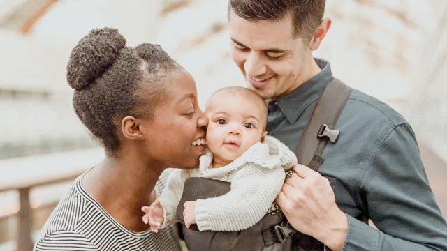 a couple out with their baby properly strapped into a baby carrier, one of our baby milestones and everyday victories for new parents