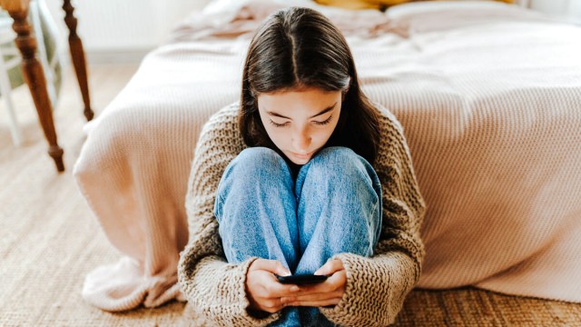 a young girl on her smartphone that has one of the best parental control apps installed