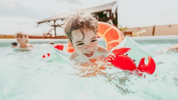 kid swimming in pool with puddle jumpers