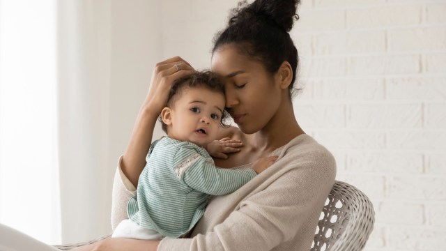 a tired mom holding her baby who is looking at the camera