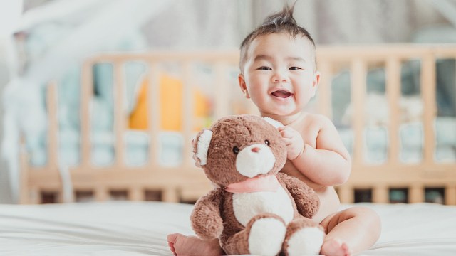 a baby holding a teddy bear who is named one of the top baby names 2024
